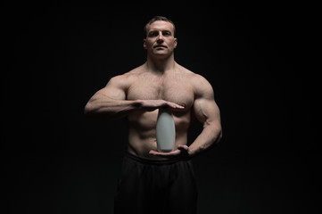 Fototapeta na wymiar Bodybuilder hold shampoo or gel bottle. Man athlete with fit torso and ab. Bodycare and hygiene for sportsman. Spa bath or shower cosmetic after training in gym