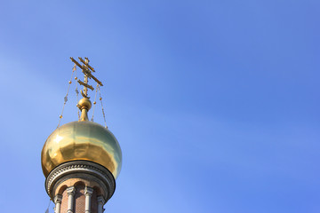 Fototapeta na wymiar Golden Dome with Cross at Church. Christian Orthodox Church Architecture Element Isolated on Empty Blue Sky Background. Religious Building Exterior of Old Historic Cathedral with Empty Copy Space.