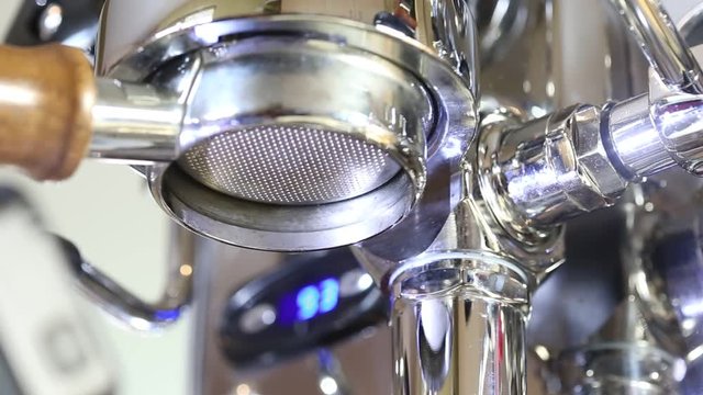 Brewing coffee at home using a nice stainless steeel coffee machine and bottomless portafilter. Barista making coffee at home.