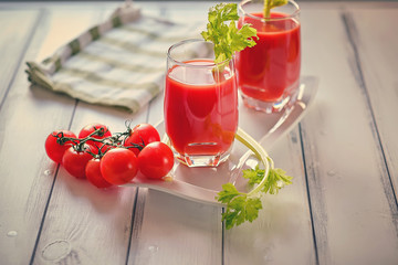 Two glasses of tomato juice on a white wooden table by the window on a sunny day
