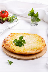Flat bread with cheese. Whole flatbread pizza on white table.