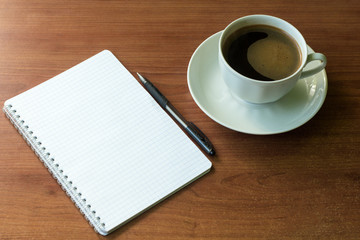 school notebook with pen and coffee Cup on table