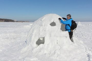 Man building an igloo on a snowy reservoir in winter, Novosibirsk, Russia