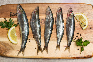 Sardinas con limón y perejil sobre tabla de madera rústica vista desde arriba