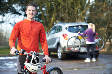 Couple Cycling Taking Mountain Bikes From Rack On Car