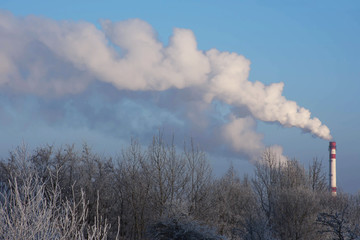 Steam from the pipe. In the distance a white smoke from a factory pipe on the background a blue sky.