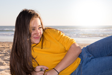 Pretty teenager girl lying on the beach with the sea and horizon in the background