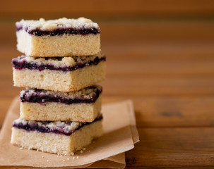 Stack of cake or cookies with jam or marmalade with sweet crumbs, cinnamon and nuts on a parchment paper.