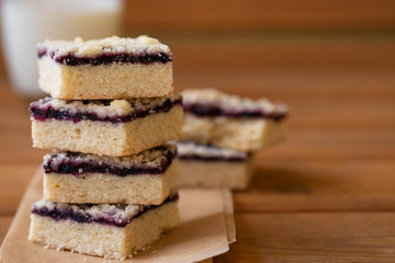 Stack of cake or cookies with jam or marmalade with sweet crumbs, cinnamon and nuts on a parchment paper.