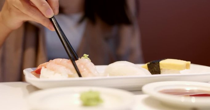 Woman enjoy Japanese sushi in restaurant