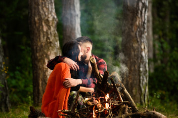 Man with woman hugs and kissing near bonfire.