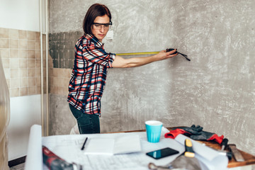 Woman measuring wall in kitchen