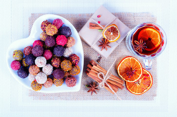 Handmade chocolate candies collection, dried oranges, spices, mulled wine, wooden pencil on wooden background.