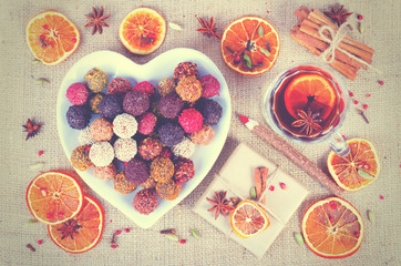 Handmade chocolate candies collection, dried oranges, spices, mulled wine, wooden pencil on wooden background.