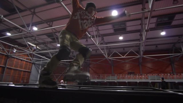 lider shooting as a man in an orange sweatshirt tries to perform a trick of a unity on rollers, slow motion