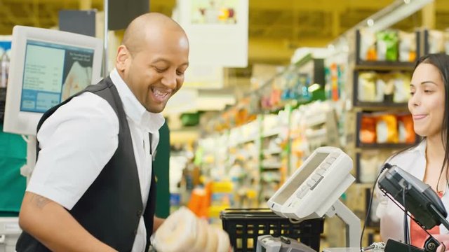 Couple Walk Through Check Out Counter And Exchange Smiles With The Cashier