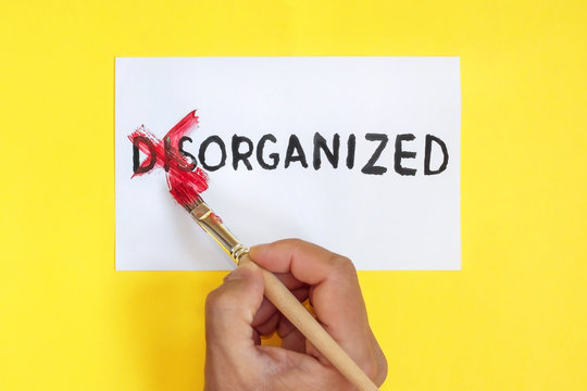 disorganized is organized concept. Hand with brush. corrected word disorganized on yellow background.
