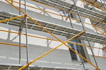 scaffolding near a new house, building exterior, construction and repair industry, white wall and...