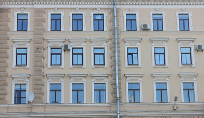 Fototapeta na wymiar Building Facade Classic Architecture with Windows in Row. Symmetric Old Historical Minimalist House with Soft Beige and Brown Stoned Walls. Exterior Front View of Traditional City Center Building.