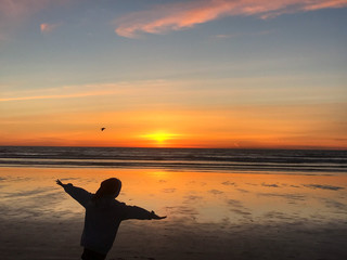 Boy imitating bird on beach