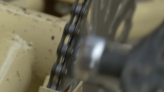 Oiled bicycle roller chain running through the cog teeth.