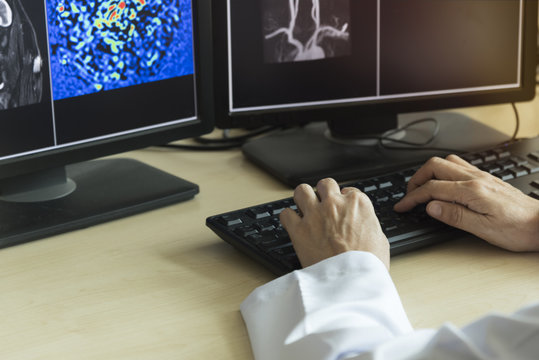 Doctor using computer to look MRI in monitor