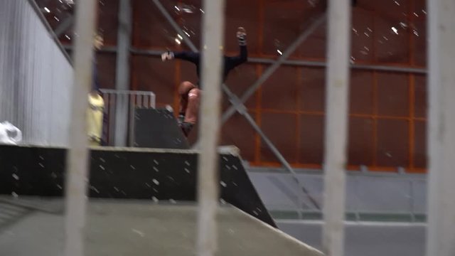 A man with dreadlocks in a multi-colored helmet does the trick on the ramp and falls, slow motion