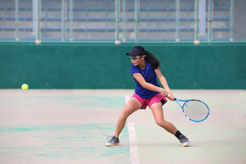 バックハンドを打つ女子ジュニアテニスプレイヤー
