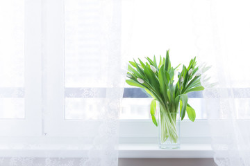 Bouquet of tulips in glass vase on windowsill
