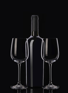 Bottle of red wine and two glasses on black background