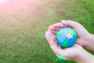 World Earth Day April 22 concept. Woman hand holding handmade globe on green grass field background.