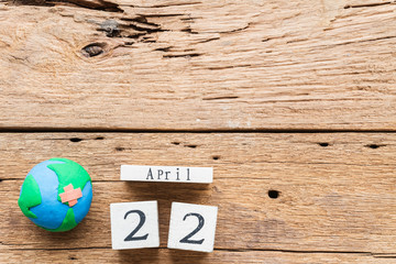 Wooden Block calendar for World Earth Day April 22  and handmade globe with Earth Day text on wooden table background texture.