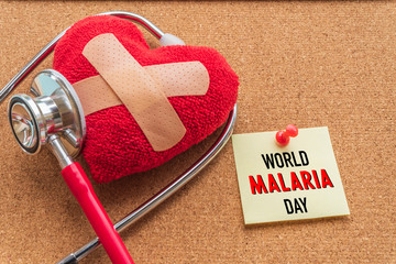 World MALARIA day April 25, Healthcare and medical concept. Stethoscope, handmade red heart, thermometer and yellow Pill on blue Pastel wooden table background texture.