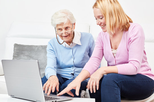 Junge Frau zeigt Seniorin am Laptop das Internet