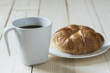 A cup of coffee and a bread on wooden background