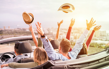 Happy people having fun in convertible car in summer vacation - Young tourist friends traveling in...