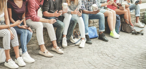 Young friends using smartphones and drinking coffee outdoor