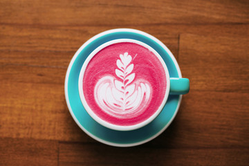 Healthy trendy beetroot latte with latte art in ceramic cup on wooden table. Top view.
