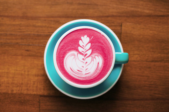 Healthy trendy beetroot latte with latte art in ceramic cup on wooden table. Top view.