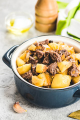 Pork stew with potato in a pot on concrete background. Selective focus, space for text. 