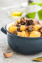 Slow cooked meat potato stew in a pot on concrete background. Selective focus, space for text. 