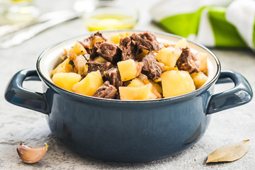 Slow cooker beef potato stew in a pot on concrete background. Selective focus, space for text. 