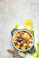 Spicy slow cooker lamb potato stew in a pot on concrete background. Top view, space for text.