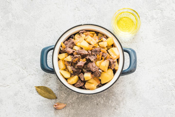 Old feshioned meat potato stew in a pot on concrete background. Top view, space for text.