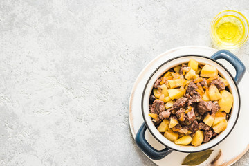 Lamb potato stew in a pot on concrete background. Top view, space for text.