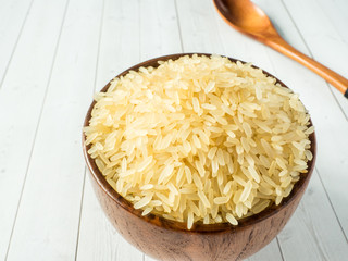 Parboiled rice groats in a wooden bowl on a light background