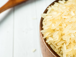 Parboiled rice groats in a wooden bowl on a light background