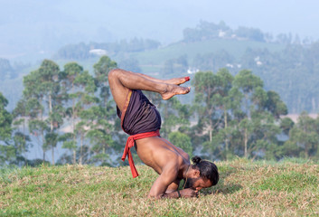 Indian man doing yoga exercises on green grass in Kerala, South India