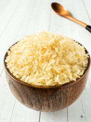 Parboiled rice groats in a wooden bowl on a light background