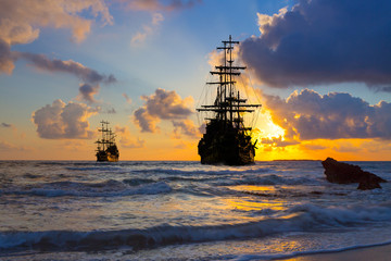 Pirate ship at the open sea at the sunset